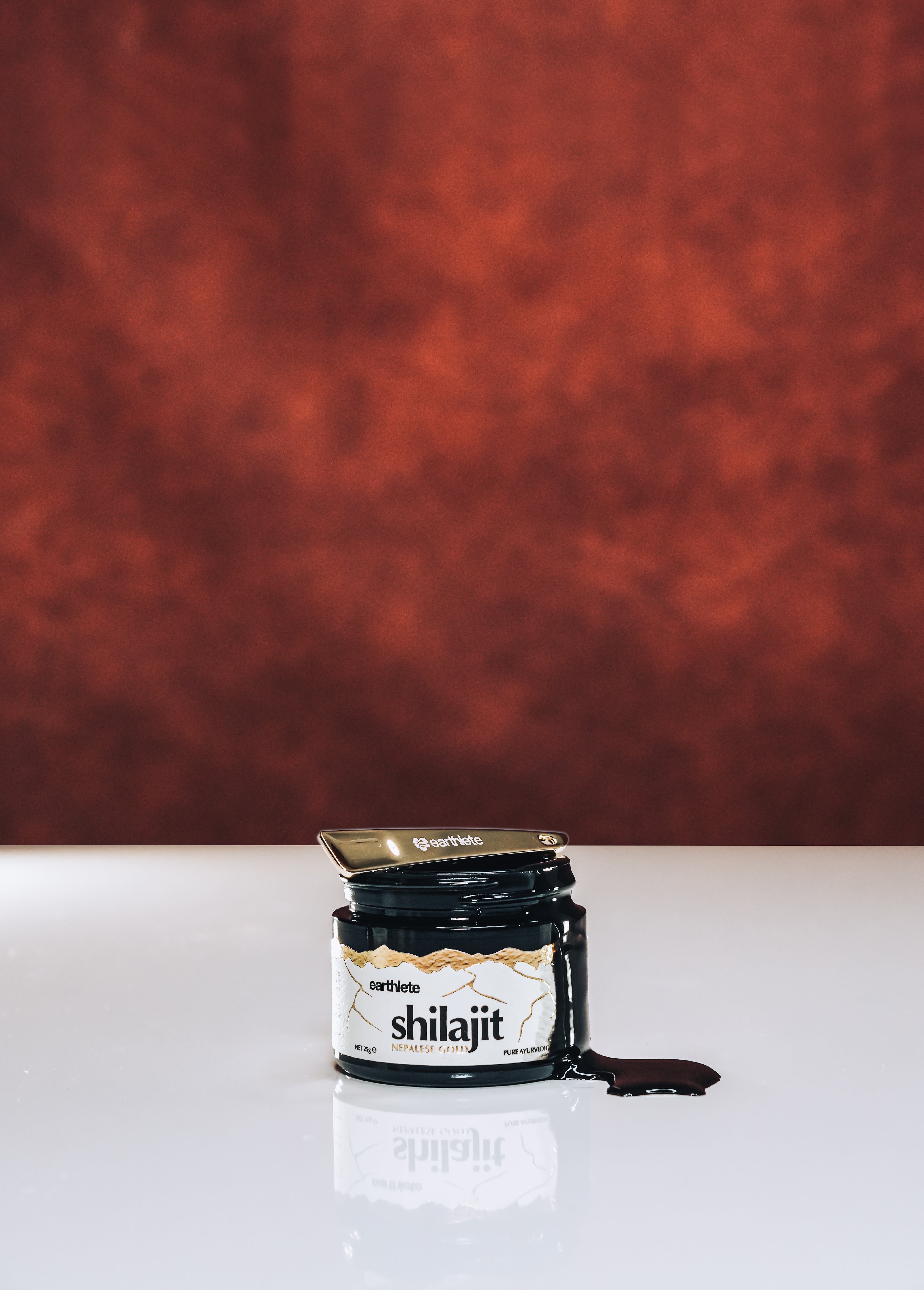 Jar of shilajit on a white surface with a red textured background