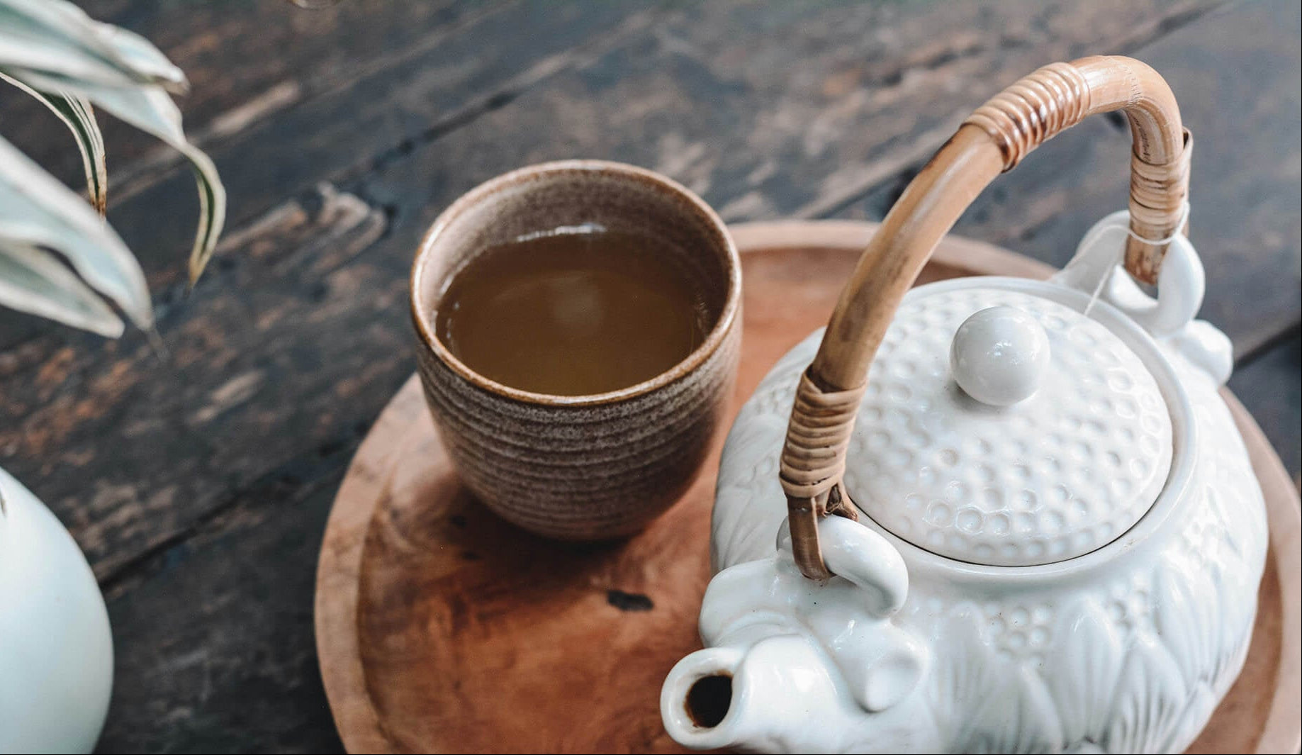 ceremonial teapot and tea in a clay pottery mug on a wooden tray with a dark wood table